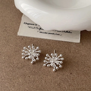 Detailed macro view of silver starburst earrings on a vintage aesthetic background