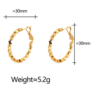 Close-up of golden geometric textured hoop earrings with 30mm diameter dimensions