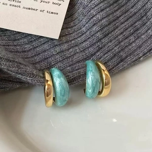 Vue détaillée des boucles d'oreilles doubles en métal doré et résine marbrée bleue
