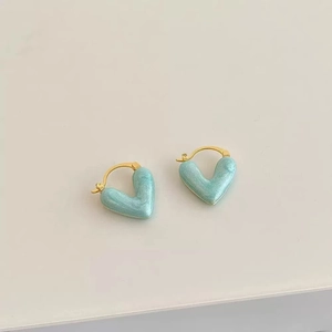 Vue macro de boucles d'oreilles cœur dorées avec émail vert menthe fini nacré
