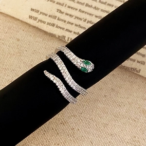 Macro detail of silver snake ring with white pavé zircons and green gemstone eyes