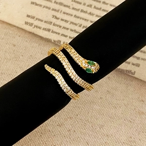 Macro shot of gold snake ring with white pavé zircons and green gemstone eyes