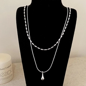 Double-layered silver necklace with teardrop pendant on a black velvet neck display