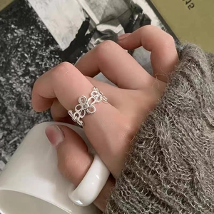 Dettaglio anello a fiori con zirconi indossato mentre si tiene una tazza di caffè