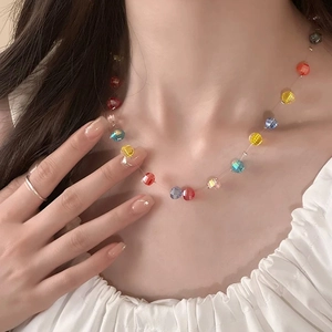 Close-up of colorful faceted pumpkin beads on a clear invisible cord fashion necklace