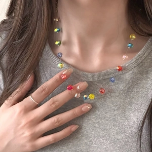 Detail of colorful faceted crystal beads on a clear wire showing a floating neck effect