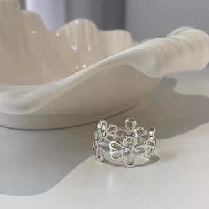 Anello con fiori traforati in argento e zirconi su uno sfondo minimalista ed elegante