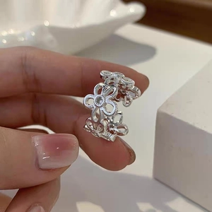 Dettaglio anello in argento a fiori con zirconi incastonati e fascia aperta regolabile