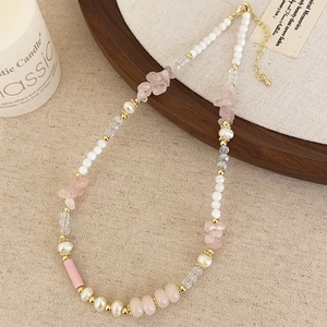 Macro detail of freshwater pearls, pink stones, and gold beads on a beaded necklace