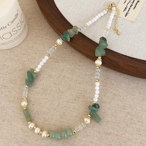 Detail of freshwater pearl and green stone beaded necklace on a rustic wooden tray