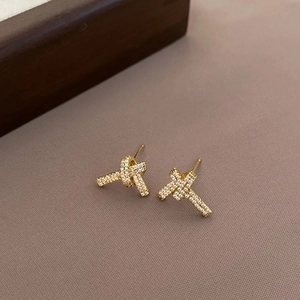 Vue détaillée des boucles d'oreilles nœud doré avec oxydes de zirconium sur tissu rose