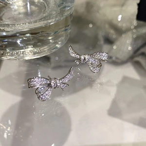Vue macro de boucles d'oreilles nœud en cristal avec pavé étincelant sur fond verre