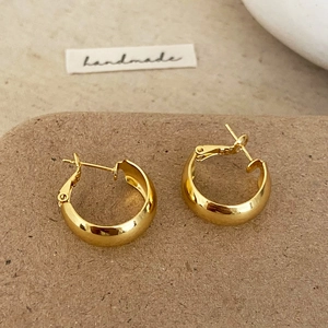Macro shot of minimalist thick gold hoop earrings with high-polish metallic finish