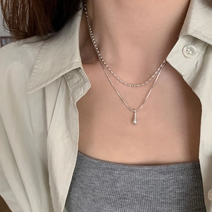 Detail of double-layer silver necklace with bead chain and waterdrop pendant
