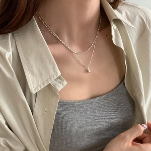 Detail of double-layer silver necklace with waterdrop pendant on model's neck