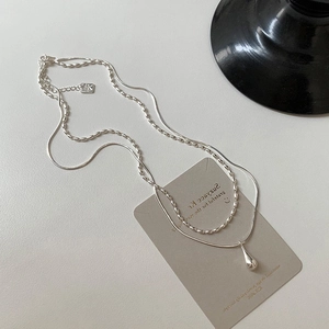 Detail of silver double-layered necklace featuring a polished water drop pendant