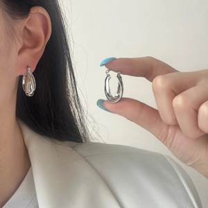 French minimalist silver twisted hoop earrings for women shown on model and in hand
