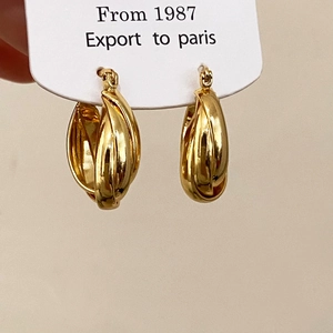Detail of glossy gold-finish twisted hoop earrings displayed on a white minimalist card