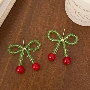 Vue détaillée des boucles d'oreilles cerise avec perles de cristal vert et pierres rouges