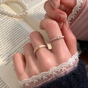 Elegant cream enamel and zircon rings shown on a hand with vintage aesthetic props