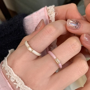 Detail of cream and pink enamel rings featuring a rectangular zircon on the gold band