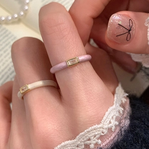 Detail of pink and white enamel rings featuring rectangular zircon stones on hand