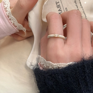 Detail of cream enamel ring featuring a rectangular zircon stone and gold trim