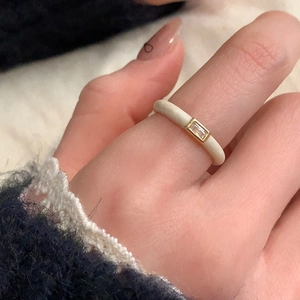 Detailed close-up of cream enamel ring with a rectangular zircon stone on model
