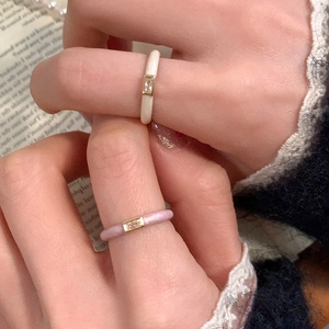 Close-up of minimalist gold enamel rings in cream and pink featuring small zircon stones