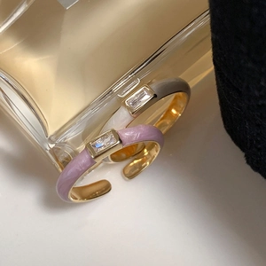 Detail of lavender and beige enamel rings with zircon stones on a luxury background