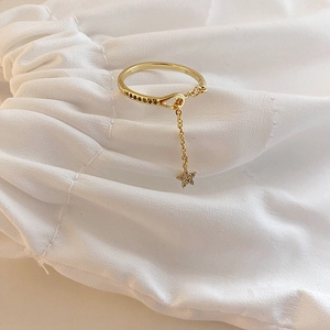 Adjustable gold star ring with cubic zirconia pendant on white fabric background