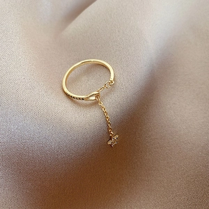 Detailed close-up of a golden star pendant ring with zircon on a luxury silk background