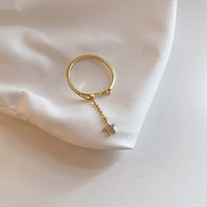 Detailed view of a gold star charm ring with zircon stones on soft silk fabric