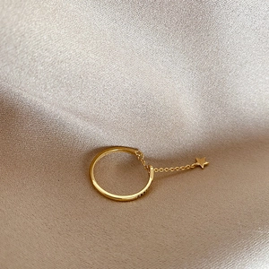 Detail of gold zircon star ring with adjustable chain on elegant beige satin fabric