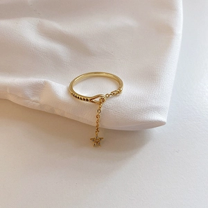 Detailed view of a gold star charm ring with zircon inlay and elegant chain detail