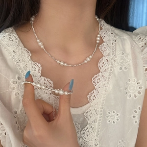 Elegant pearl and silver bead necklace and bracelet set shown on model in lace outfit
