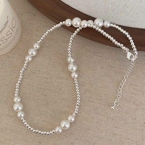 Detailed view of elegant pearl beaded necklace with silver beads and lobster clasp closure