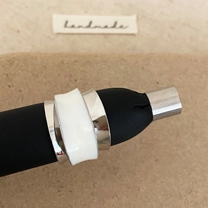 Detail of silver double-layer ring with white enamel inlay on a handmade display