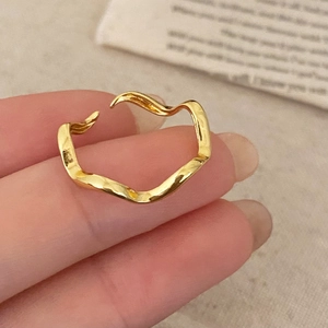 Close-up of a minimalist golden wavy textured open ring with a polished metal finish
