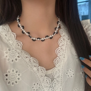 Elegant black and white faux pearl choker necklace featuring floral beaded patterns