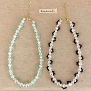 Handmade pearl necklaces with colorful beads and gold lobster clasps on beige fabric