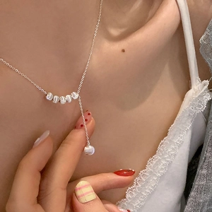 Gros plan d'un collier en Y argenté orné de perles métalliques et d'un pendentif perle