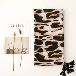 Detalle de bufanda con estampado de leopardo, textura suave y borlas negras largas