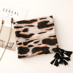 Primer plano de bufanda con estampado de leopardo y borlas negras sobre fondo suave