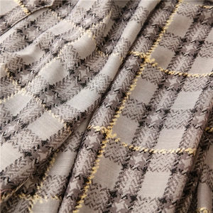 Detail of grey herringbone fabric scarf with yellow and black plaid and gold gilding