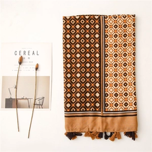Detailed flat lay of geometric print scarf with fringes alongside a lifestyle magazine