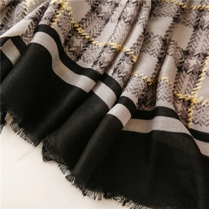 Close-up of grey and white plaid scarf with yellow stripes and black fringe edges