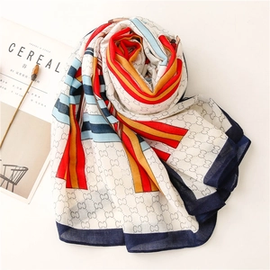 Detail of soft linen scarf featuring colorful chain letters and vibrant striped patterns