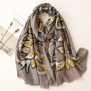 Detail eines grauen Paisley-Schals mit goldenen Blumenmustern und feinen Fransen