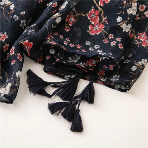 Detailed macro view of dark blue floral scarf with red plum blossoms and fringe